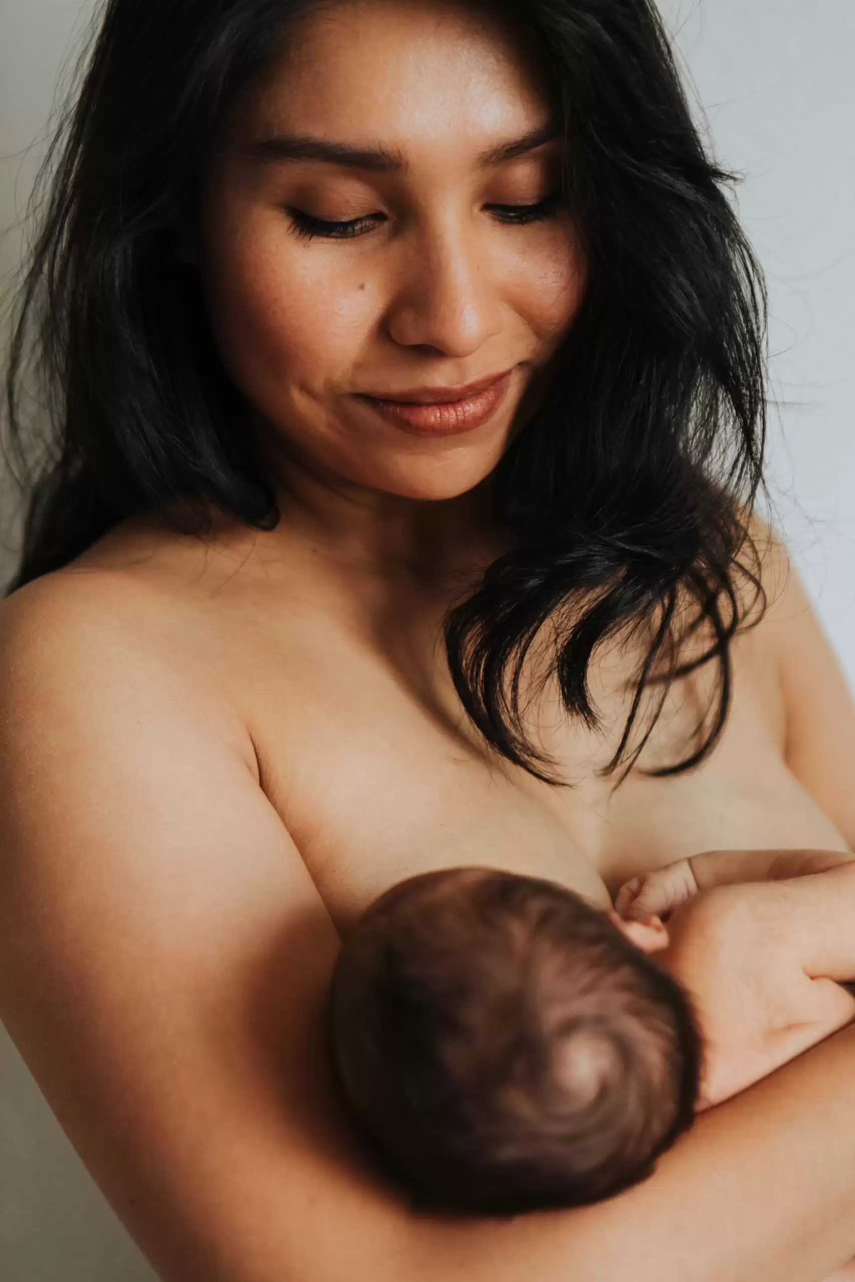 Mujer amamantando a su bebé, momento que influye directamente en los cambios del busto con la edad debido a la actividad de las glándulas mamarias.