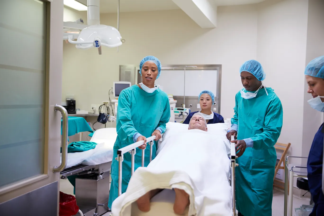 Imagen de un hombre recostado en una camilla, siendo trasladado al quirófano para realizarse un procedimiento daddy makeover enfocado en el torso y el rostro