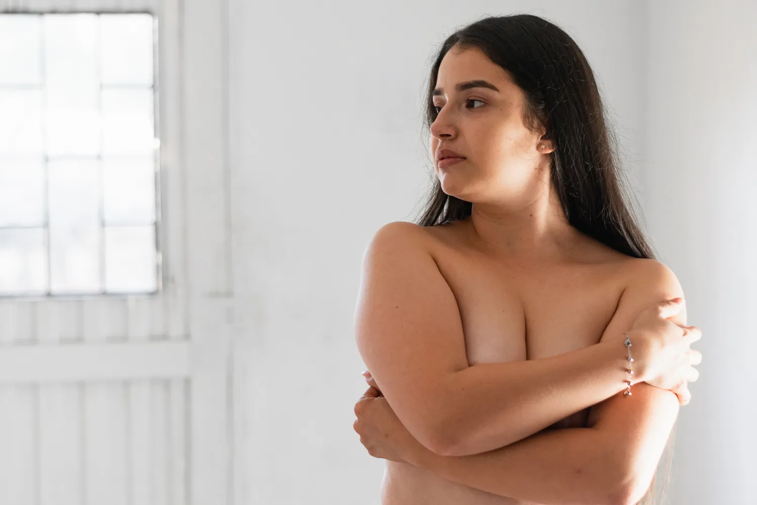 Mujer con gesto de tristeza tocando su abdomen y cuerpo con desesperación por no ver los resultados esperados, clara representación del impacto psicológico Mommy Makeover en la autoestima