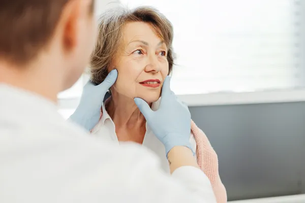 Mujer madura en consulta estética mientras una doctora especialista revisa cuidadosamente la piel y el rostro para valorar la mejor opción de lifting facial