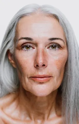 Retrato frontal de una mujer mayor con cabello plateado y piel madura, destacando los resultados de un tratamiento con luz pulsada intensa