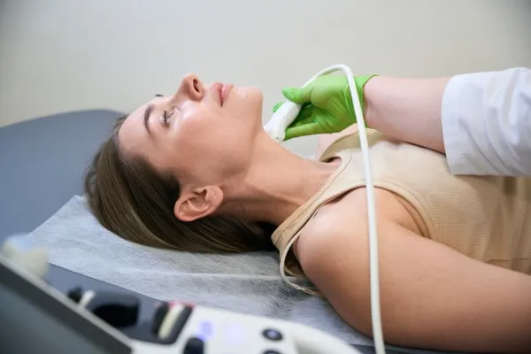 Paciente acostada recibiendo un procedimiento en el cuello con una sonda que podría ser para tratamiento HIFU ultrasonido focal de alta intensidad