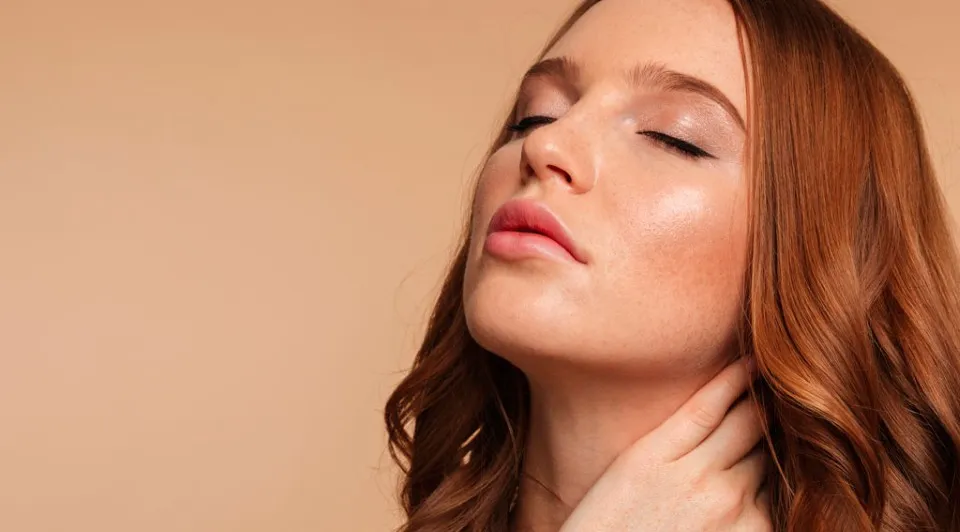 Primer plano de una mujer de perfil, con la cabeza ligeramente inclinada hacia atrás, mostrando una línea de la mandíbula y cuello esculpidos y sin grasa.